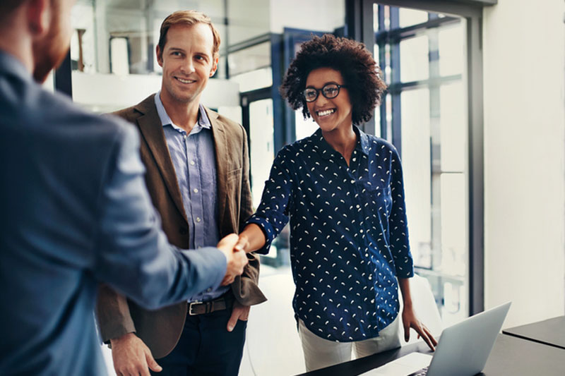 Business people shaking hands in sunny office.