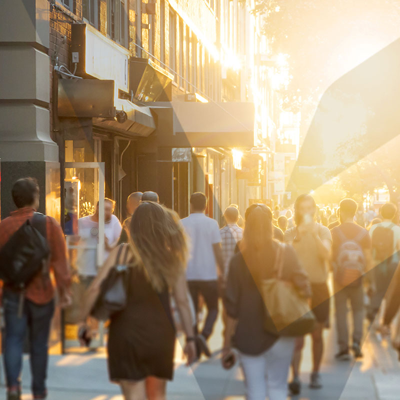 Group of people walking on city sidewalk.